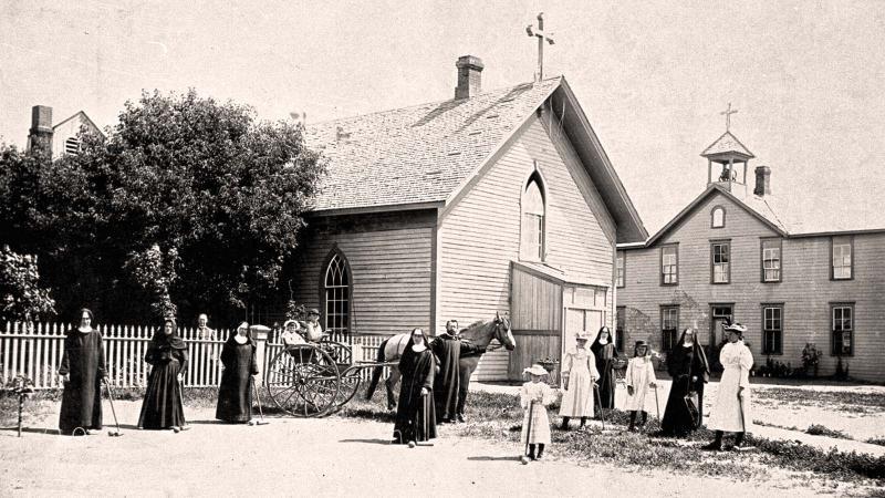A photo from 1878 of religious people standing outside church and in front of horse drawn carriage.